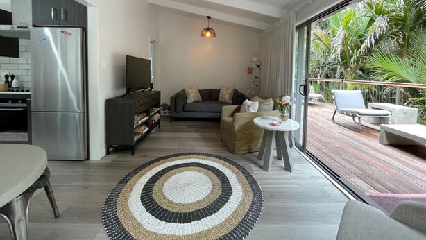 Een moderne woonruimte met een keuken, een bank, een televisie en een balkon met planten.