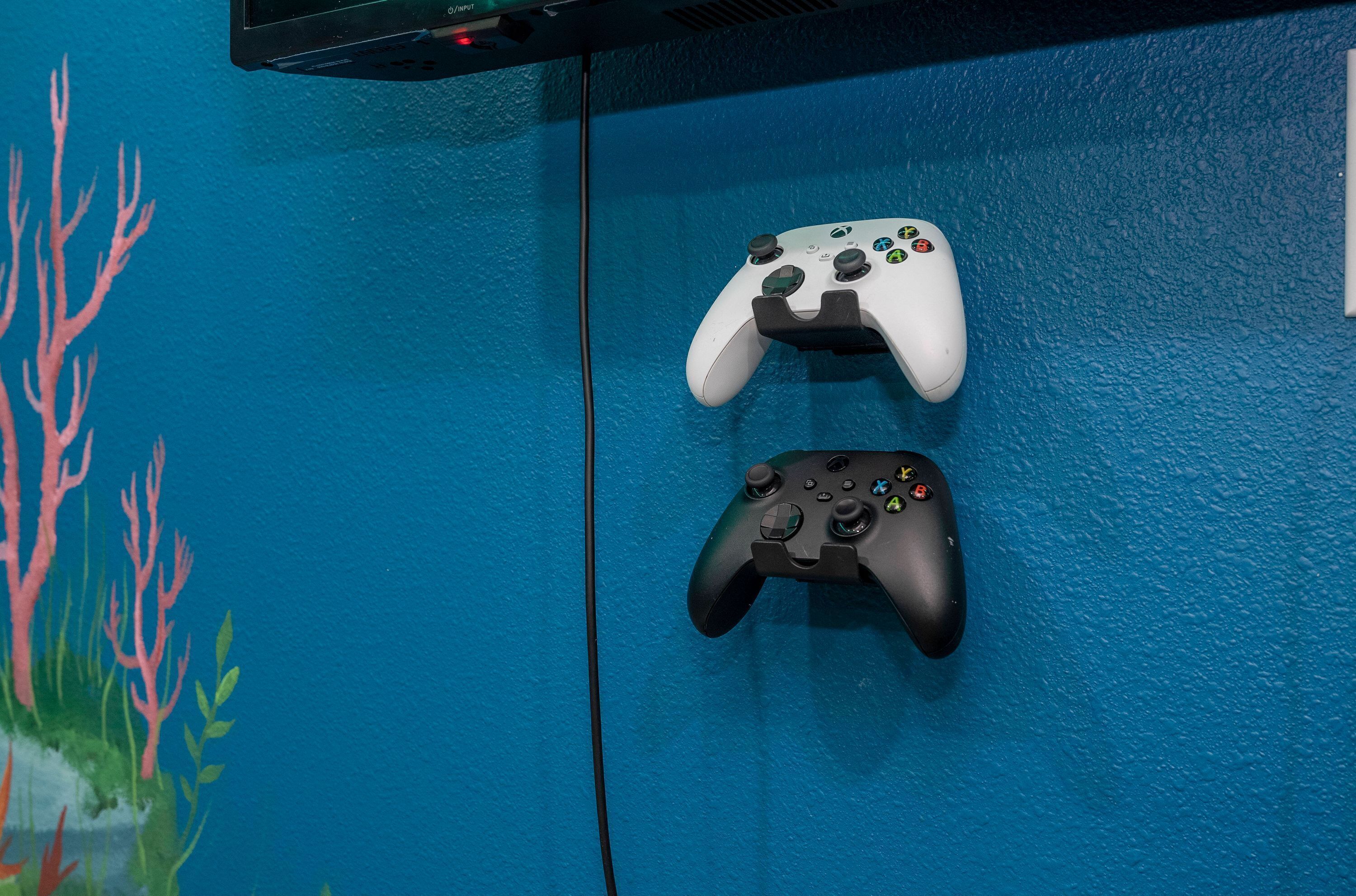 Two game controllers mounted on a blue wall with a coral reef mural.