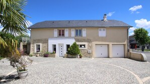 A two-story house with a driveway, a garage, and a small garden area with potted plants. - Lou Quillé - UZEIN - Gîte (UZEIN)