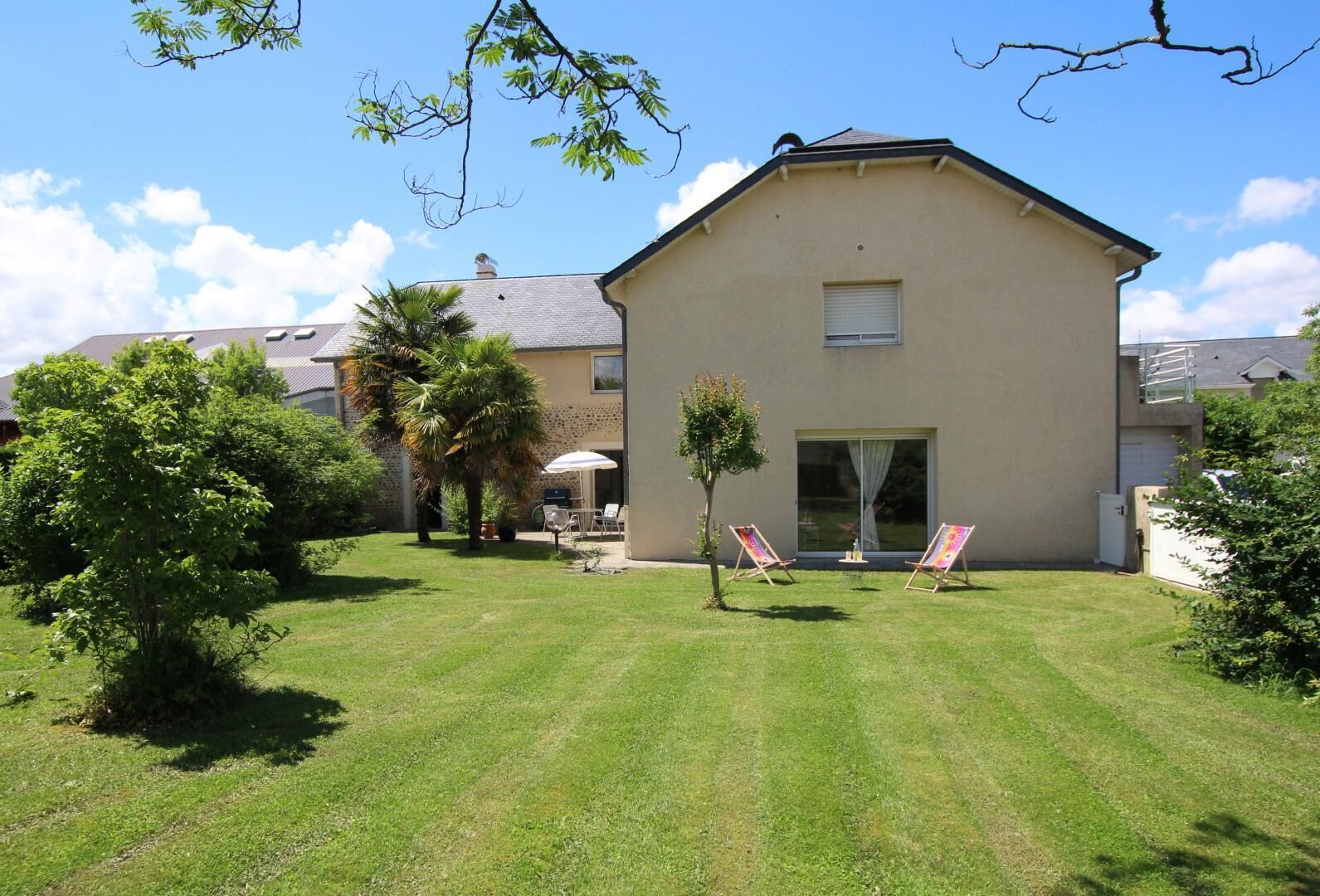 A residential building with a well-maintained lawn, two outdoor chairs, and a small tree.
