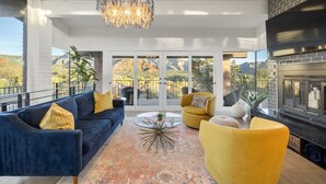 A modern living room with a blue sofa, yellow armchairs, and a glass coffee table. - Endless RedRock Views Modern Uptown Home w/Spa/Gym (Sedona)