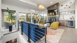 A modern living room with a blue sofa, yellow armchair, and a large window with a mountain view. - Endless RedRock Views Modern Uptown Home w/Spa/Gym (Sedona)
