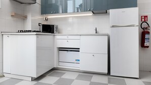 A modern kitchen with white cabinetry, a built-in oven, a microwave, and a refrigerator.