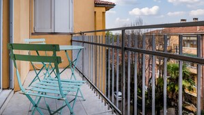 A balcony with a metal railing, a green folding chair, and a table.