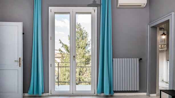 A room with a sliding glass door, a radiator, and a ceiling-mounted air conditioner.