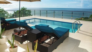 A poolside area with lounge chairs and umbrellas, overlooking a body of water. - Dream Caribbean Sea View Luxurious  Apartment, Marigot, Saint Lucia (Castries)