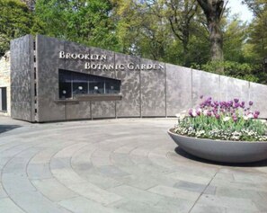 Enter the Brooklyn Botanical Garden through a striking stone facade, flanked by vibrant planters.
