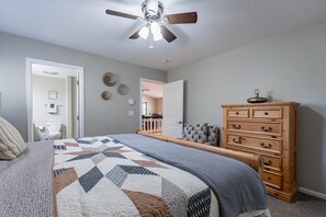 A bedroom with a bed, a wooden dresser, a ceiling fan, and a door leading to another room. - Sleeps 12-Near Lake-Family~Mountains|Cedar Escape (Show Low)