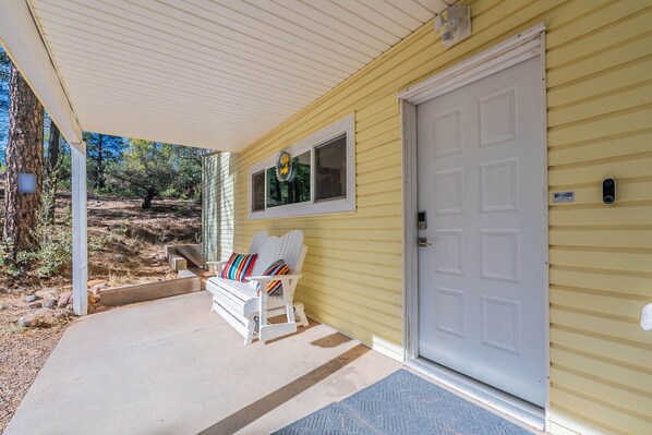 A covered porch with a white bench and a door.