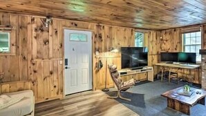 A wooden-paneled room with a television, a desk, and a chair.