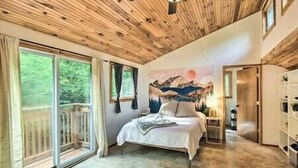 A bedroom with a bed, a painting, a wardrobe, and a balcony.