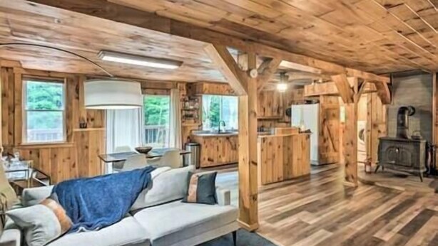 A cabin interior with a wooden floor, a sofa, a dining table, and a kitchen area.