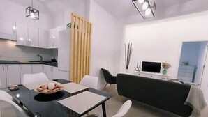 Et moderne køkken med hvide skabe, et sort spisebord og en sort sofa.