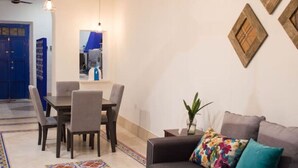 A modern living room with a sofa, a dining table with chairs, and a ceiling with exposed beams and pendant lighting. - Casa Tiago - Downtown & Romance by LAHOS (Mérida)