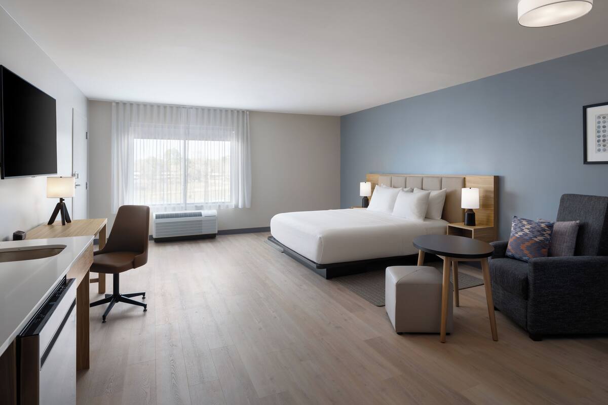 Una camera d'albergo moderna con un letto, una scrivania, una sedia, un divano e una televisione.