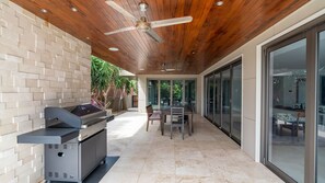 An outdoor patio with a grill, a ceiling fan, and a dining area with a table and chairs. - Clifftop Luxury With Pool ~ Ultimate outdoor experience with a private pool (Kiama)