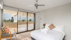 A bedroom with a bed, a chair, a ceiling fan, and a sliding glass door leading to a balcony. - Clifftop Luxury With Pool ~ Ultimate outdoor experience with a private pool (Kiama)
