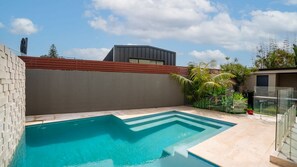 A swimming pool with a geometric design, surrounded by a low brick wall and a modern building in the background. - Clifftop Luxury With Pool ~ Ultimate outdoor experience with a private pool (Kiama)