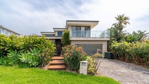 Een modern herenhuis met garage, omgeven door weelderige begroeiing en een verzorgd gazon.