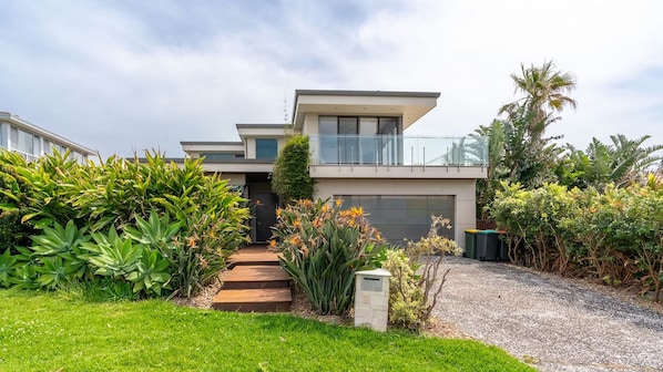 A modern two-story house with a garage, surrounded by lush greenery and a well-maintained lawn. - Clifftop Luxury With Pool ~ Ultimate outdoor experience with a private pool (Kiama)