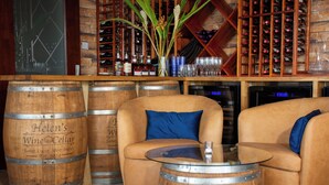 Una zona de bar con sofás de cuero, barriles de madera y una estantería para vinos.