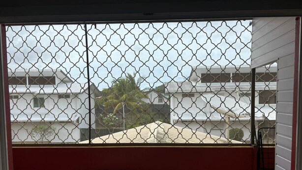Un balcone con ringhiera in metallo, un tavolino e due sedie.