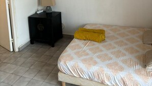 Una camera da letto con un letto, un comodino, una lampada, un quadro appeso e una porta.