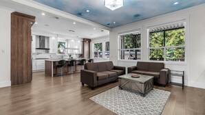 A spacious living area with a modern kitchen in the background, large windows, and a ceiling with a unique design. - Luxury Spacious House (Surrey)