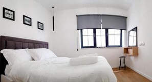 Relax in this serene bedroom with a large bed, framed artwork, and a comfortable reading nook.