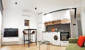 Cozy living space with a flat-screen TV, kitchenette, and comfortable sofa.