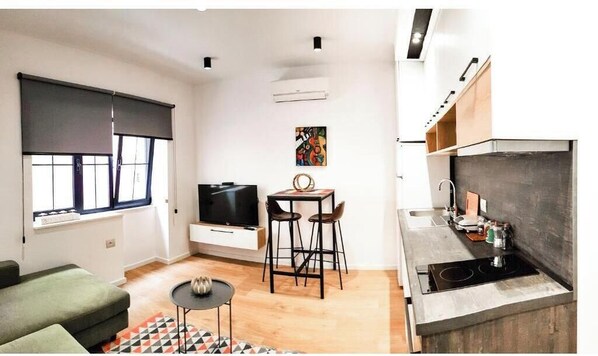 Cozy living area with a sofa, small table, and flat-screen TV.