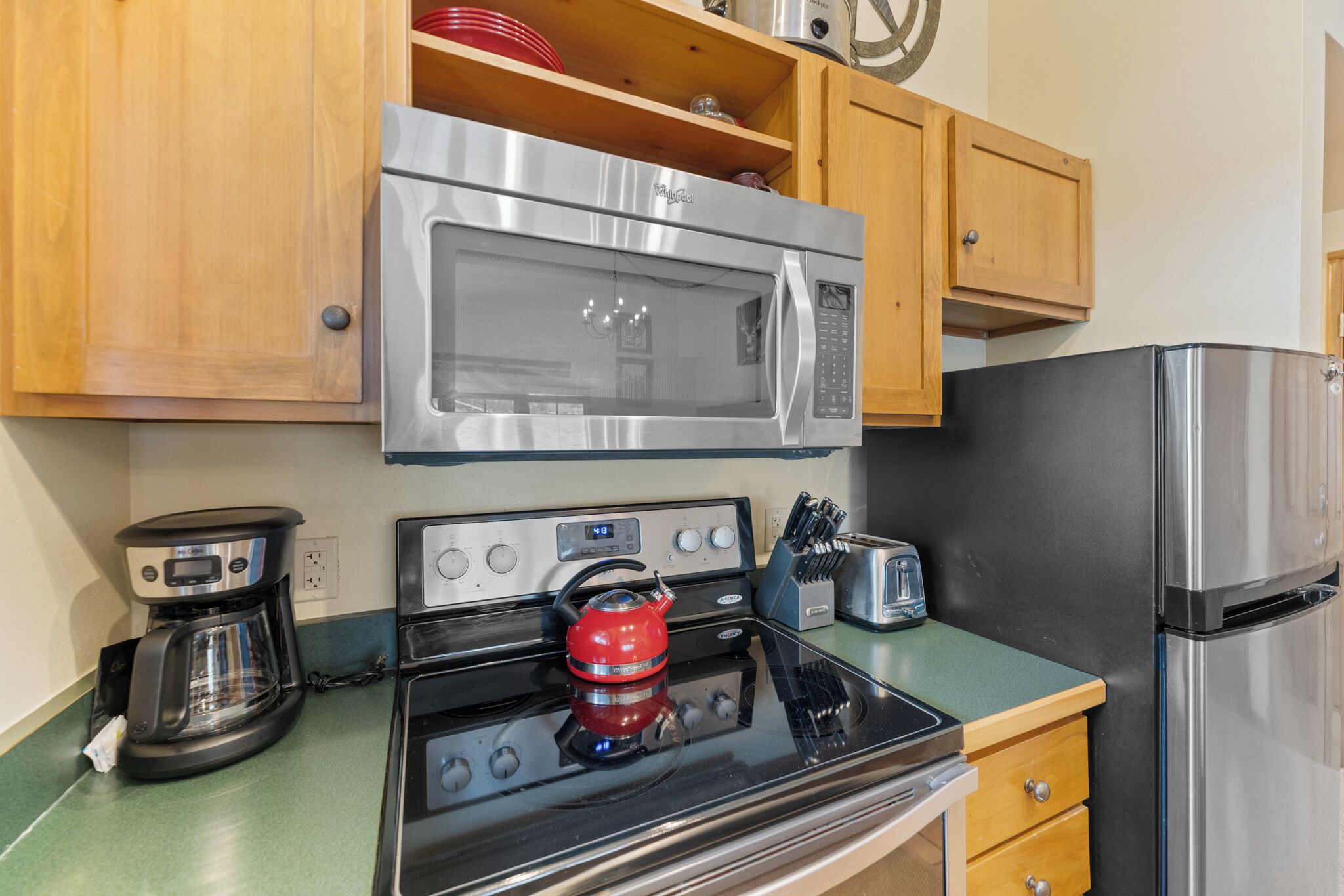 A kitchen with a stainless steel microwave, stove, and refrigerator.