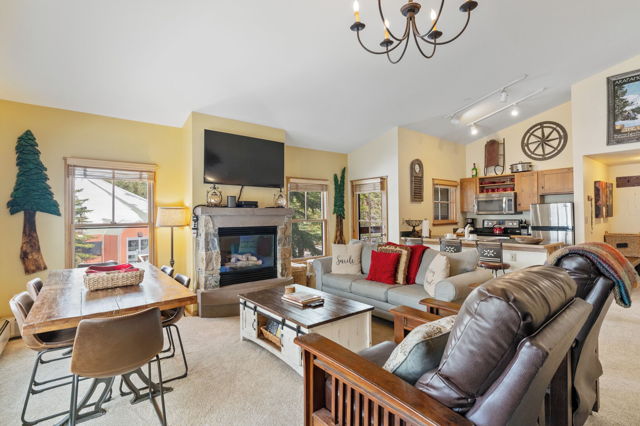 A cozy living room with a fireplace, a dining area, and a kitchen.
