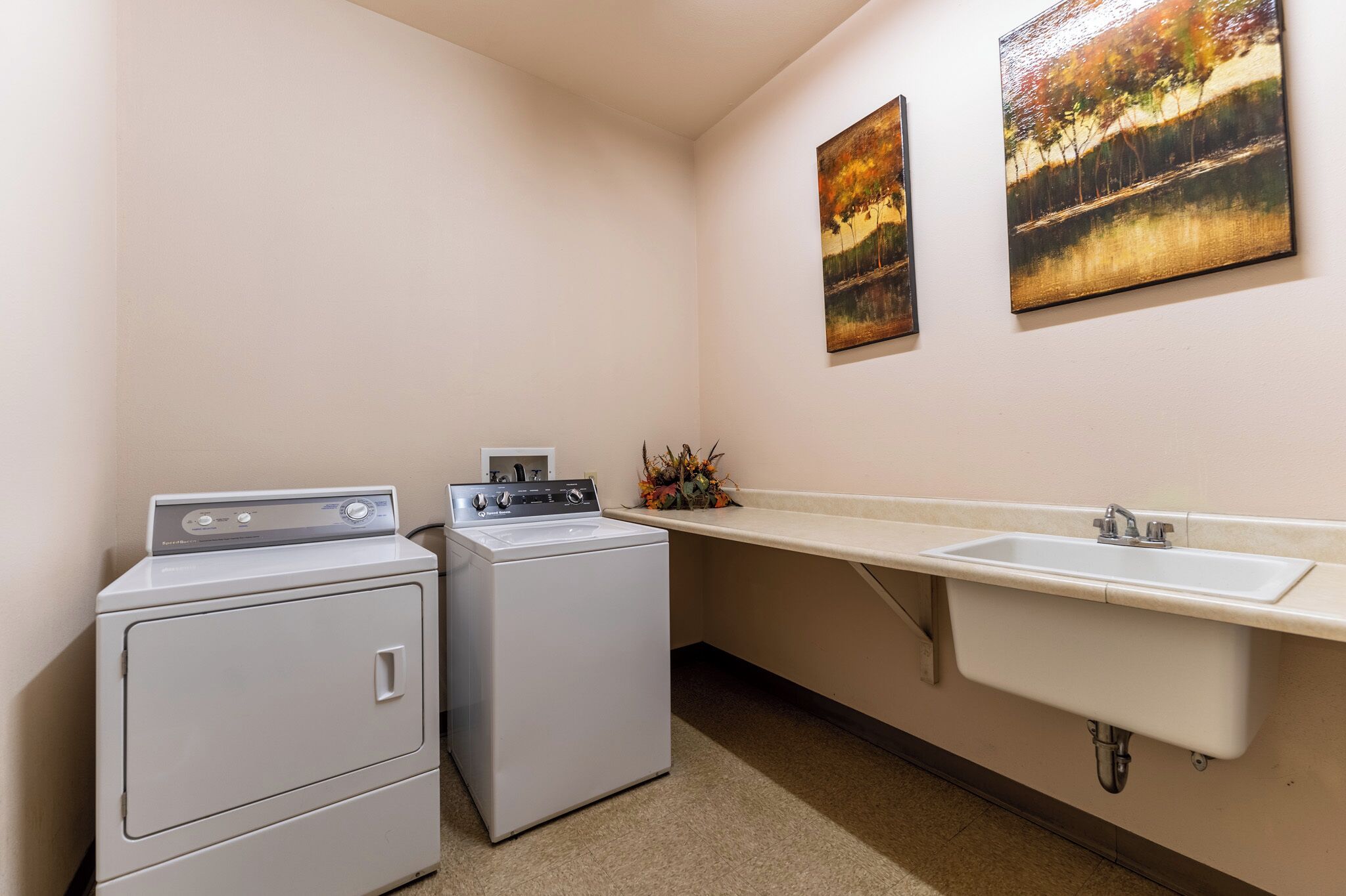 A laundry room with two washers and a sink.