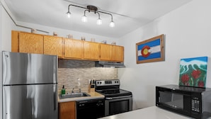 Una cocina moderna con electrodomésticos de acero inoxidable, armarios de madera y encimera blanca.