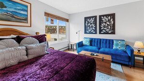 Una habitación con una cama, un sofá azul y una ventana con vistas a edificios.