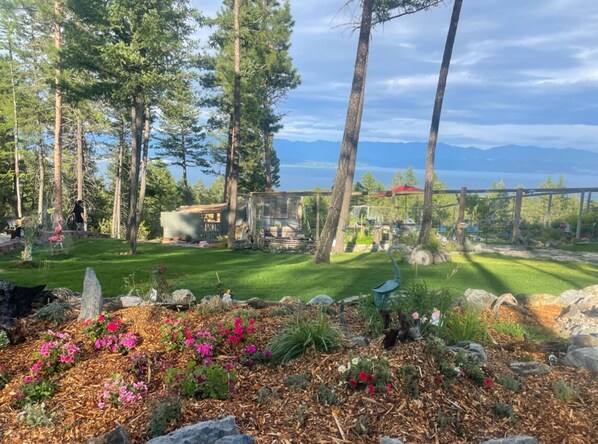Un jardin doté d’une terrasse en bois, entouré d’arbres et offrant une vue sur un lac.