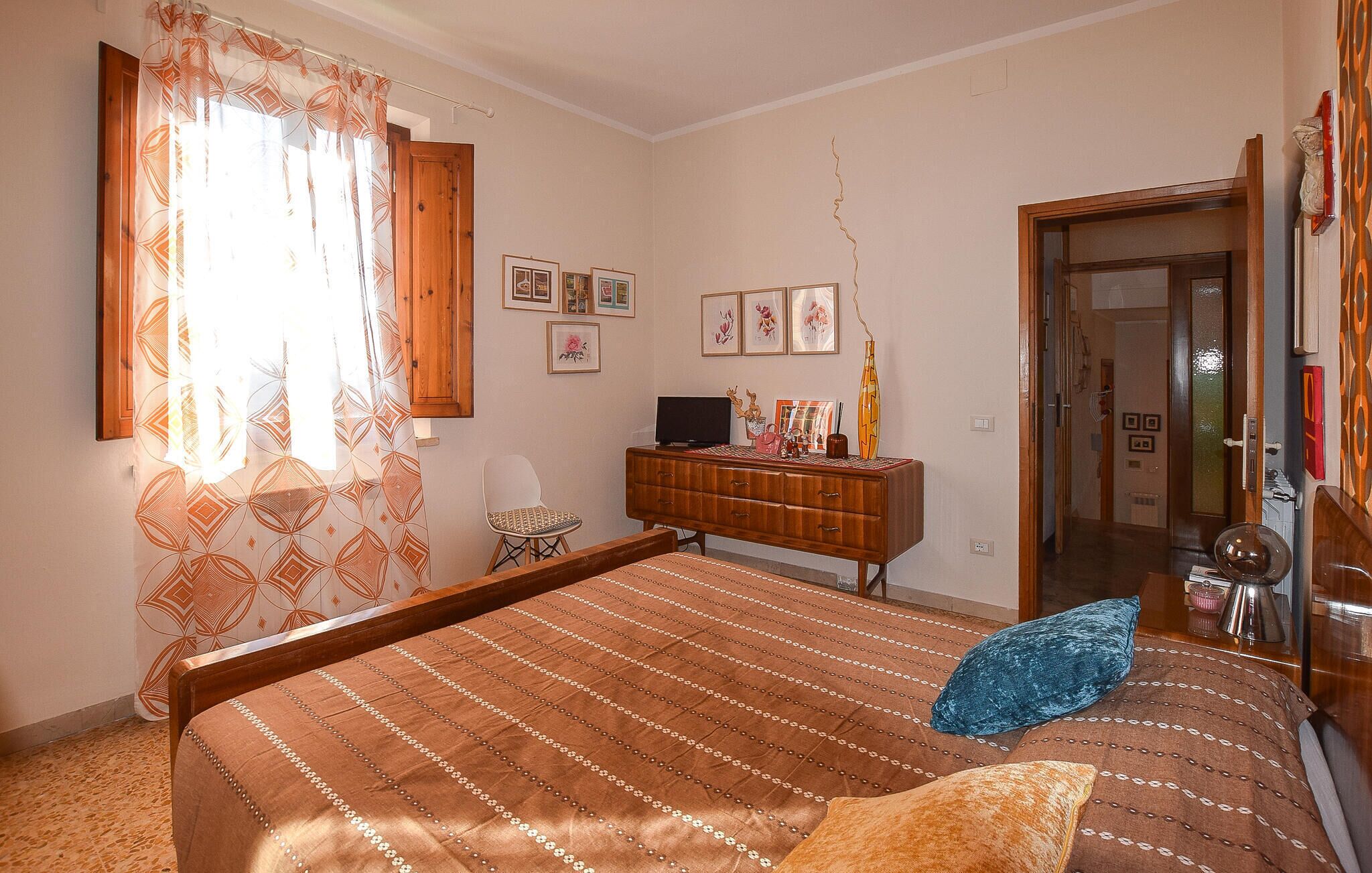 Een slaapkamer met een bed, een dressoir, een stoel en een televisie.