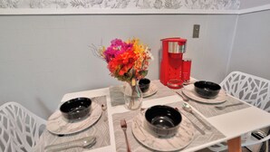 A dining table set with black bowls, a vase with colorful flowers, and a red coffee maker. - Chic and Comfy apartment centralized in Rochester (Rochester)