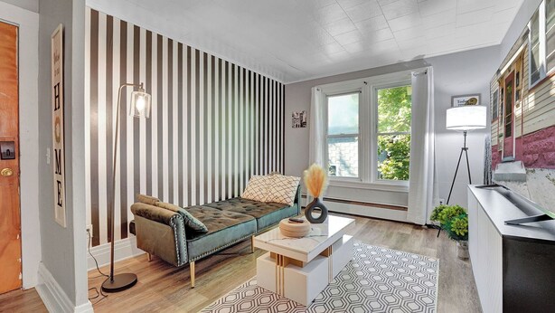 A modern living room with a striped wall, a sofa, a coffee table, and a view of the outside. - Chic and Comfy apartment centralized in Rochester (Rochester)