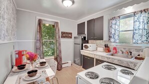 A compact kitchen with a dining area, featuring a refrigerator, microwave, stove, and a window with curtains. - Chic and Comfy apartment centralized in Rochester (Rochester)