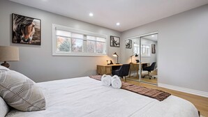 Un dormitorio con una cama grande, un escritorio, una silla y un espejo.