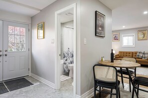 Ett modernt vardagsrum med en beige soffa, ett runt träbord och svarta stolar.