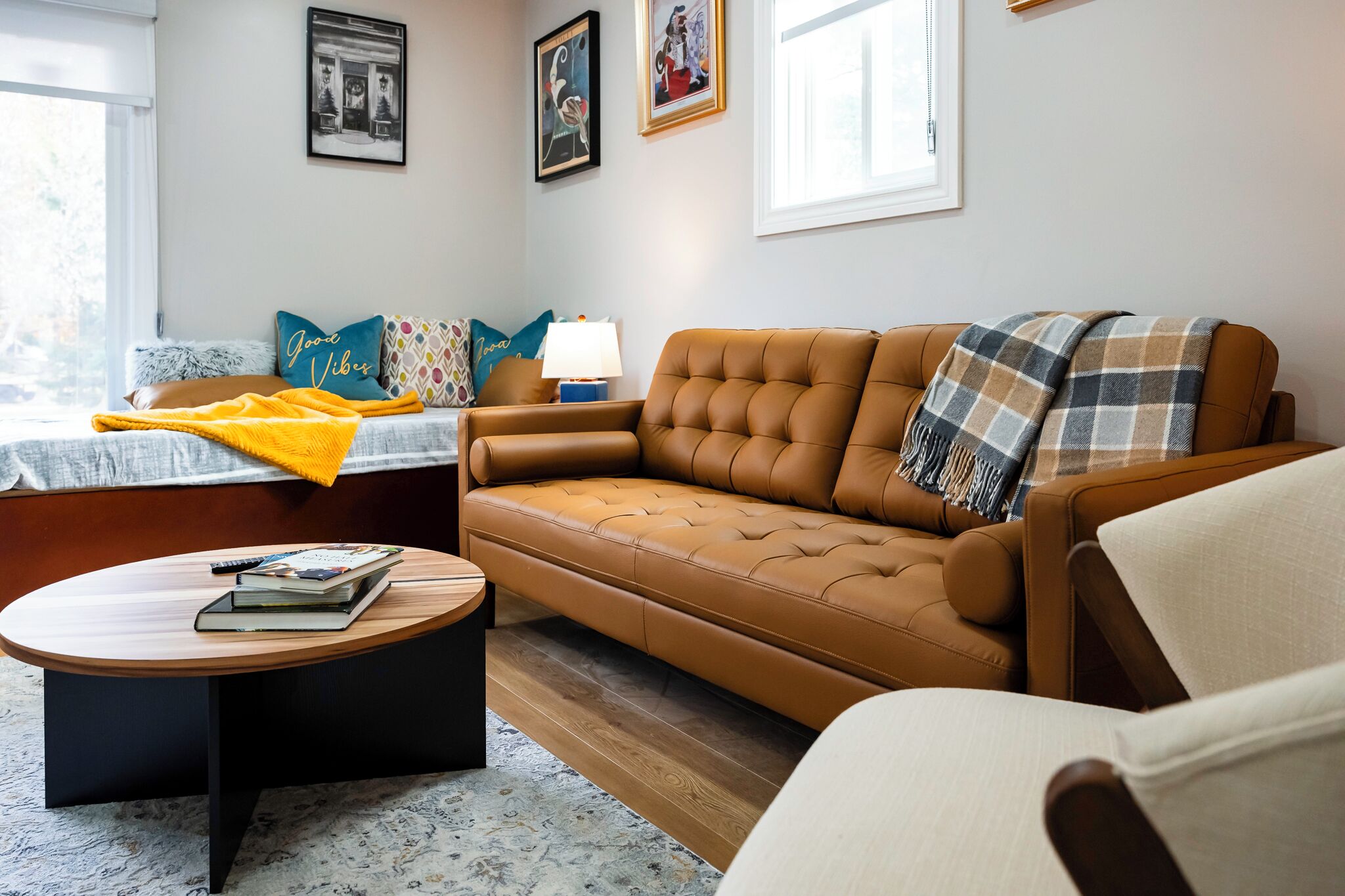 Un salon chaleureux avec un canapé en cuir marron, une table basse ronde en bois et un fauteuil beige.