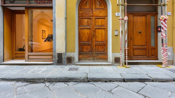 Un edificio con una gran puerta de madera, una tienda con ventana de vidrio y una calle empedrada.