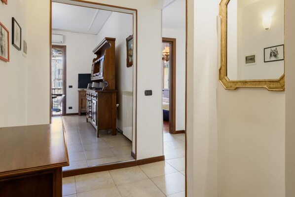 Un pasillo con una mesa de madera, una zona de cocina con estufa y un espejo en la pared.