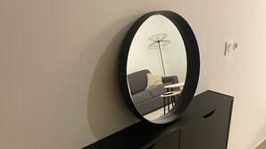 Una habitación moderna con una consola negra, un espejo redondo y un sofá.