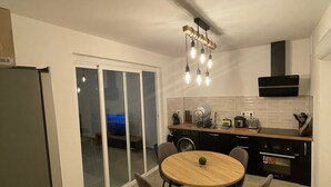 Una cocina moderna con comedor, que incluye una mesa redonda de madera, cuatro sillas, horno empotrado y campana extractora.