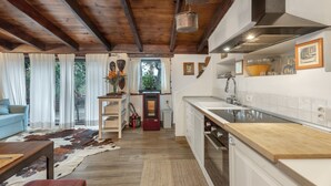 Ampla sala de estar com teto de madeira, cozinha com armários brancos e uma janela grande com cortinas.
