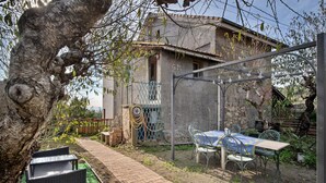 Un patio con mobiliario exterior, una pérgola y un edificio rústico al fondo.